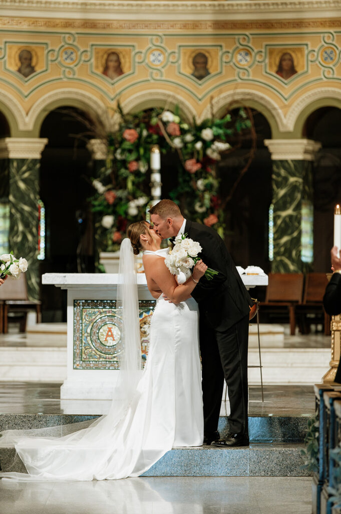 Bride and groom sharing their first kiss at the altar inside Saint Clement Parish.