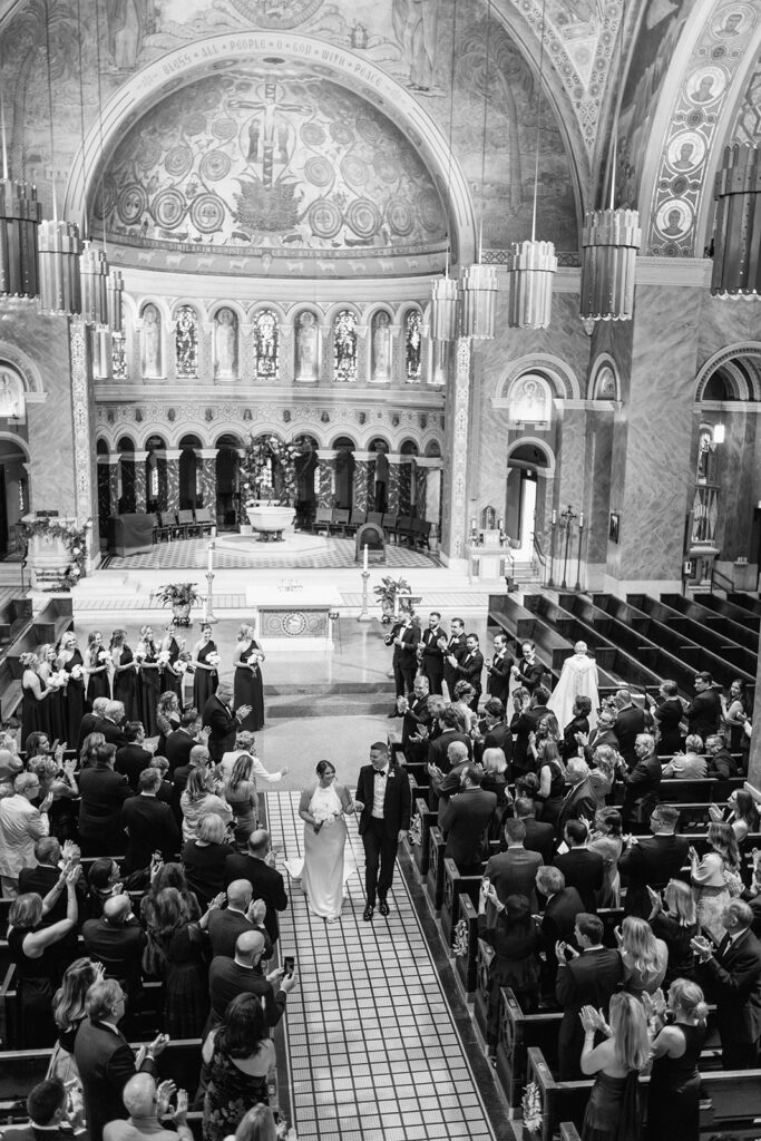 Black and white image of guests reacting during a Catholic wedding ceremony in Chicago.