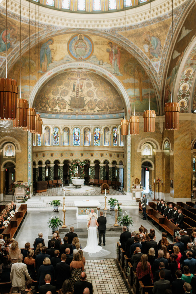 Wide view of Saint Clement Parish showing ornate arches, mosaics, and the altar during the ceremony.