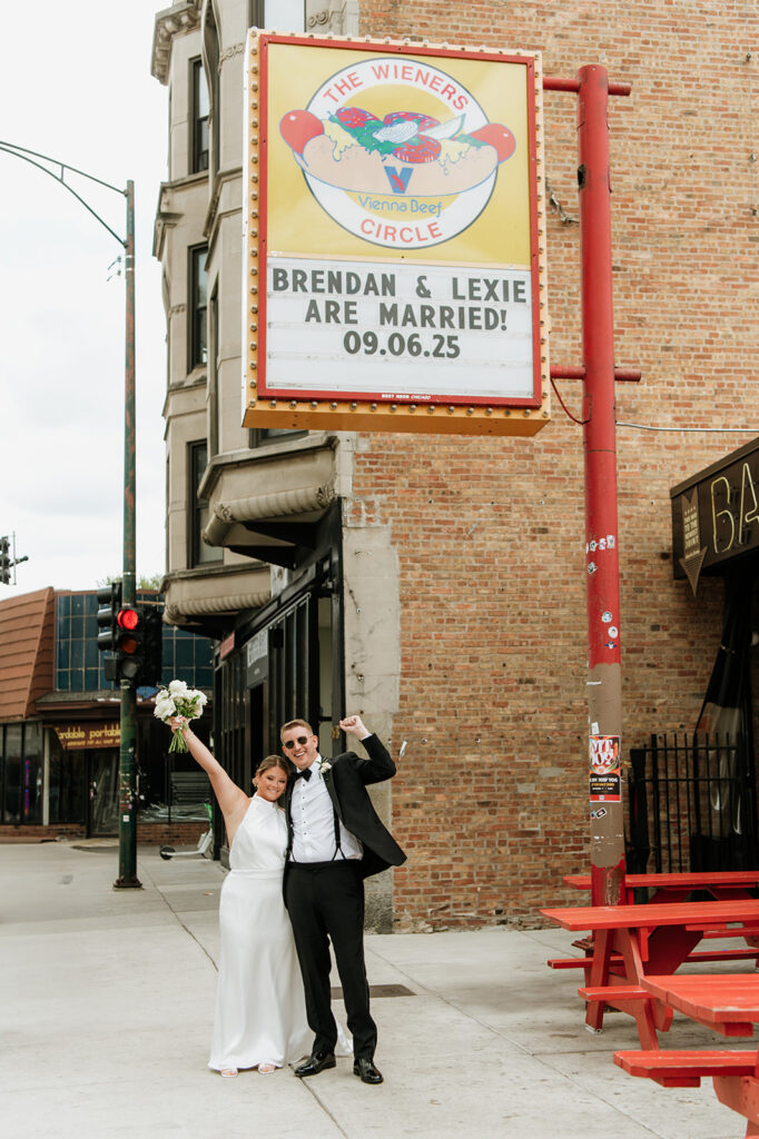 Bride and groom posing beneath the Weiner's Circle sign in Chicago.