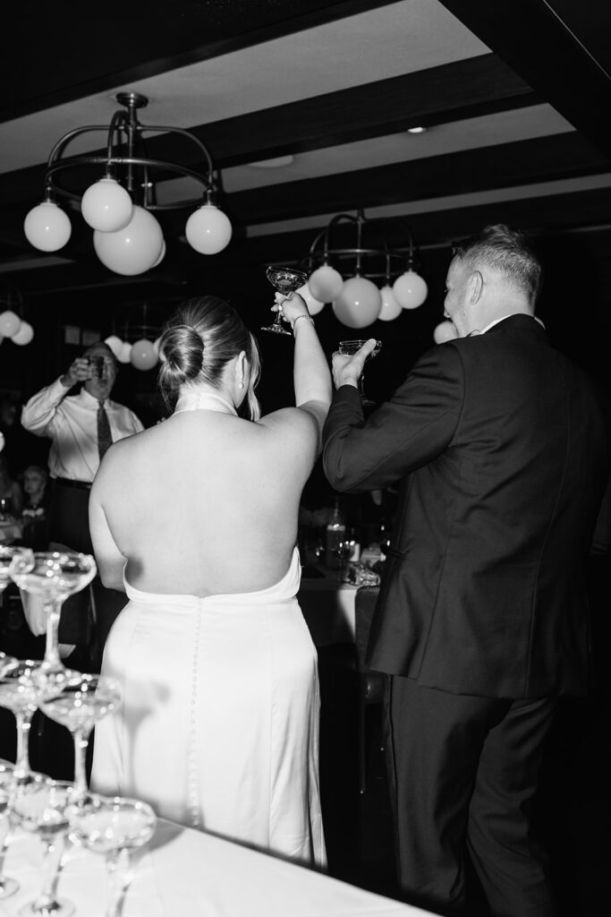 Newlyweds raising champagne glasses during speeches at a Tortoise Supper Club wedding.