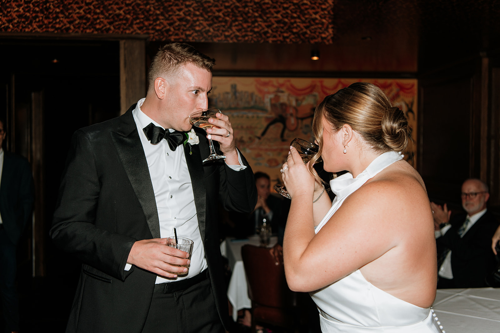 Bride and groom sipping champagne from their glasses.