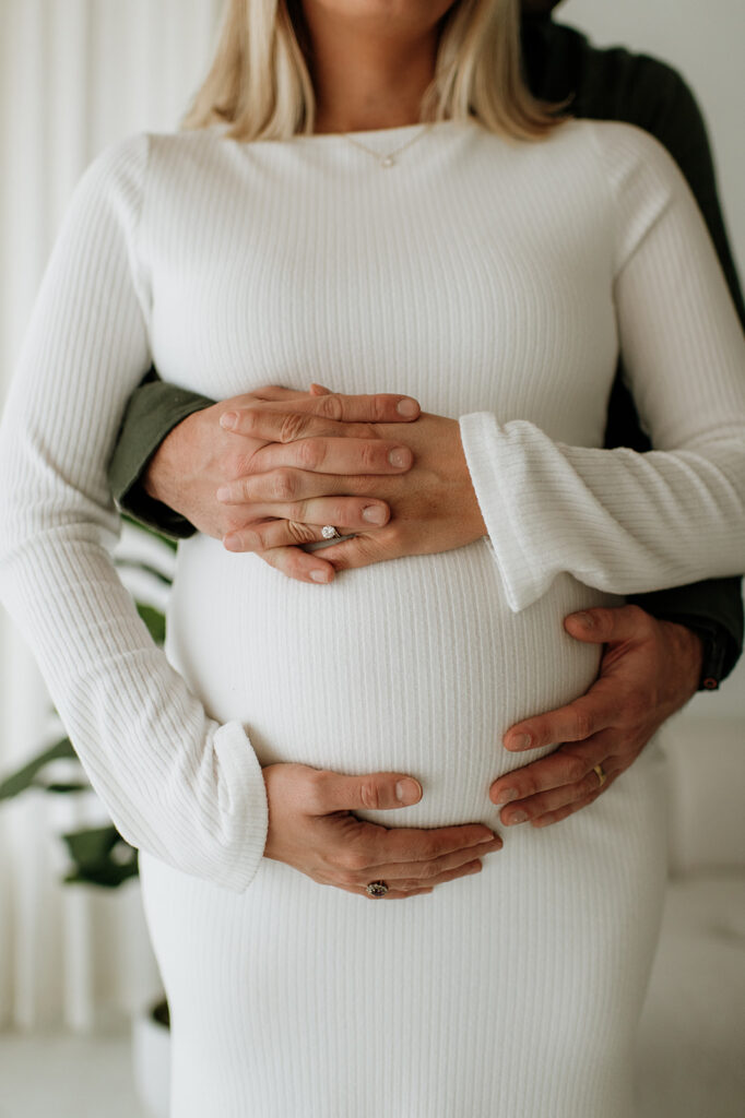 Close-up of hands resting on a baby bump during South Bend Indiana maternity photos in a studio.