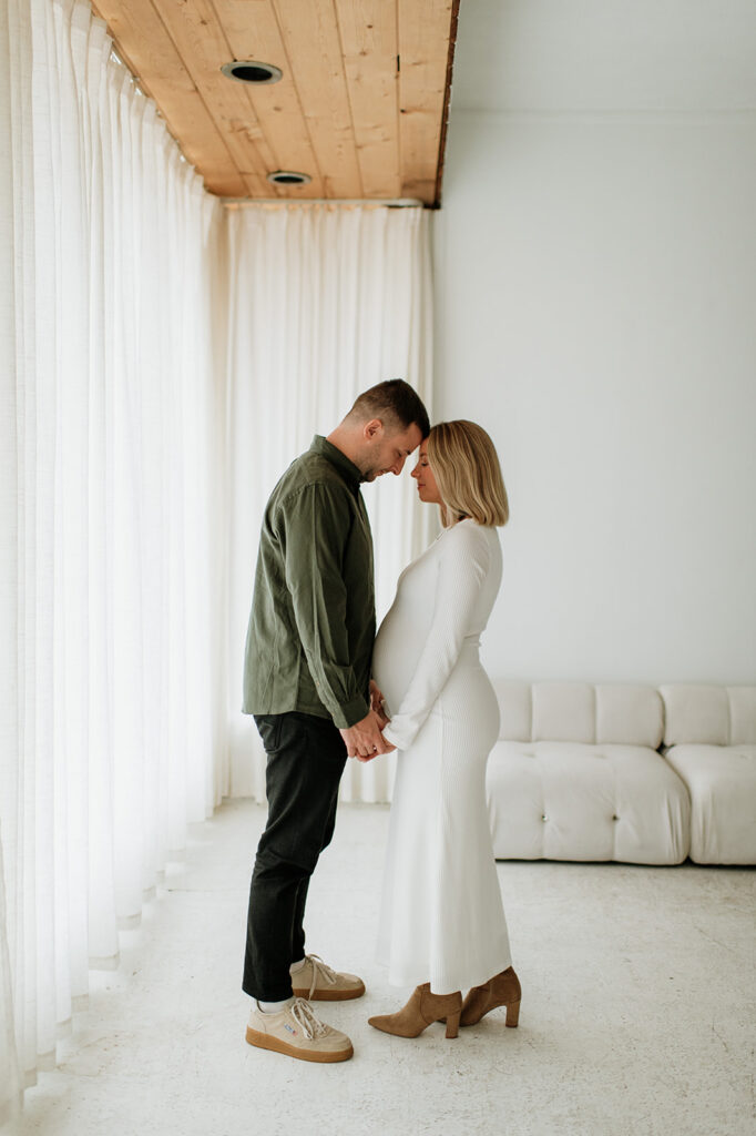 Couple standing face to face with their foreheads touching during South Bend Indiana maternity photos at Area Hall Art House.