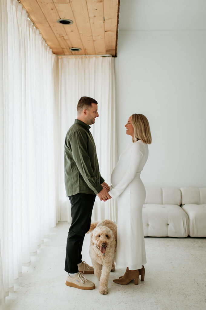 Couple standing face to face with their dog during South Bend Indiana maternity photos at Area Hall Art House.