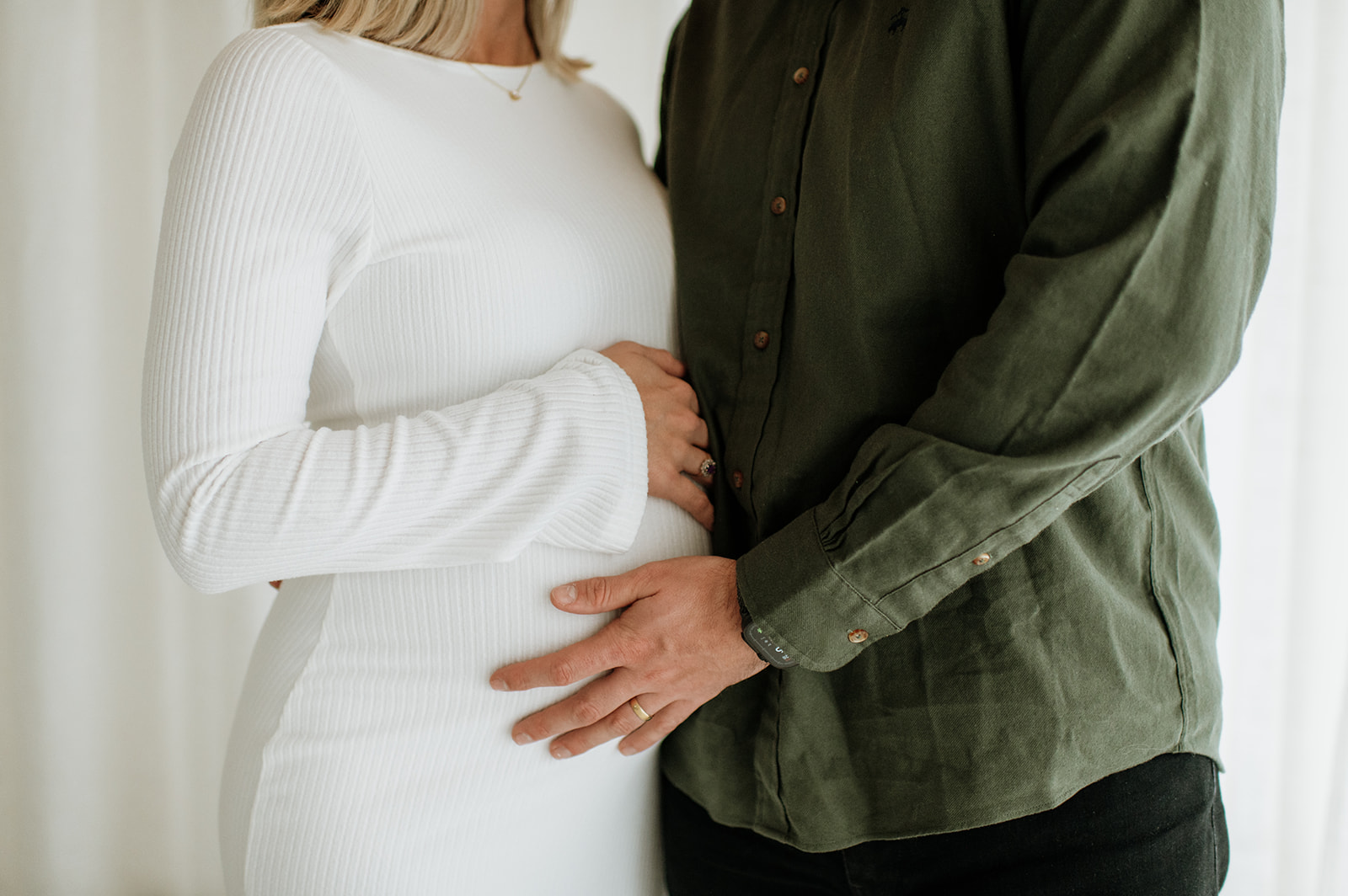 Close up shot of a man and woman holding the pregnant woman's belly during their photo session.