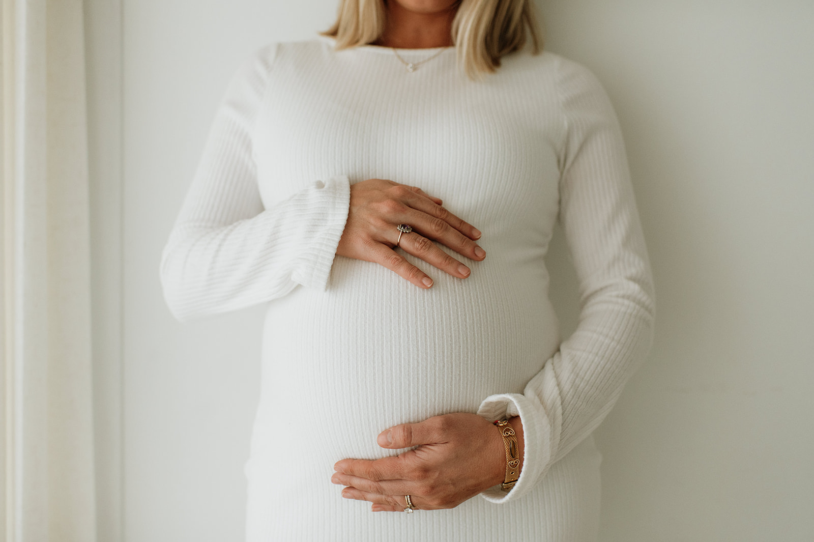 Close up shot of a bride resting her hands on her belly during her studio maternity session.