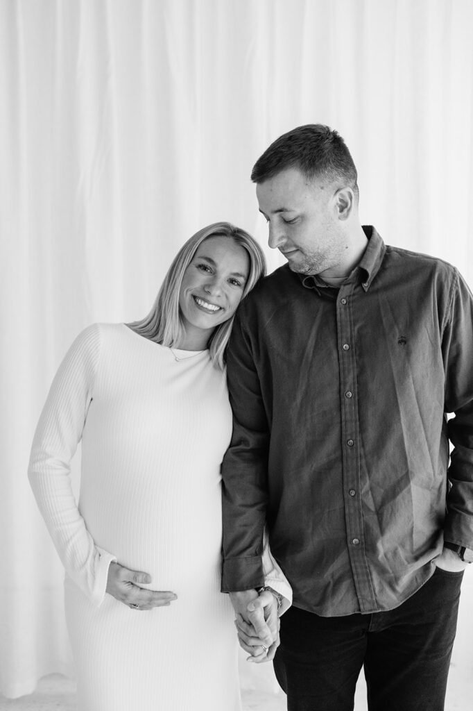 Black and white maternity photo of a couple holding hands during South Bend Indiana maternity photos.
