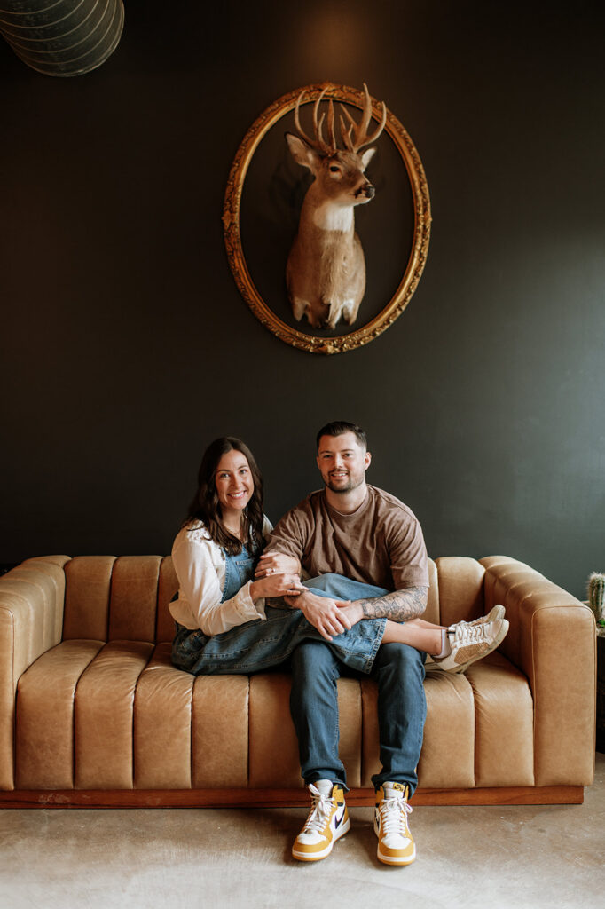 Couple sitting close together on a vintage couch during antique shop engagement photos in Indiana.