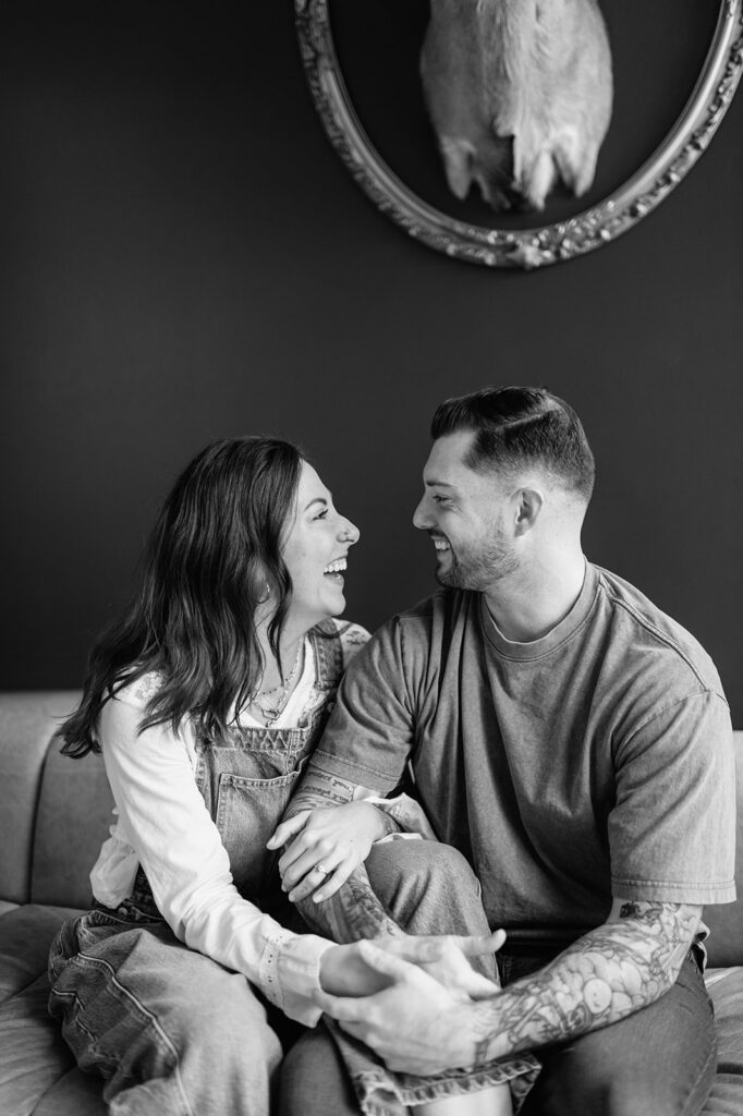 Black and white candid of couple laughing together during antique shop engagement photos.
