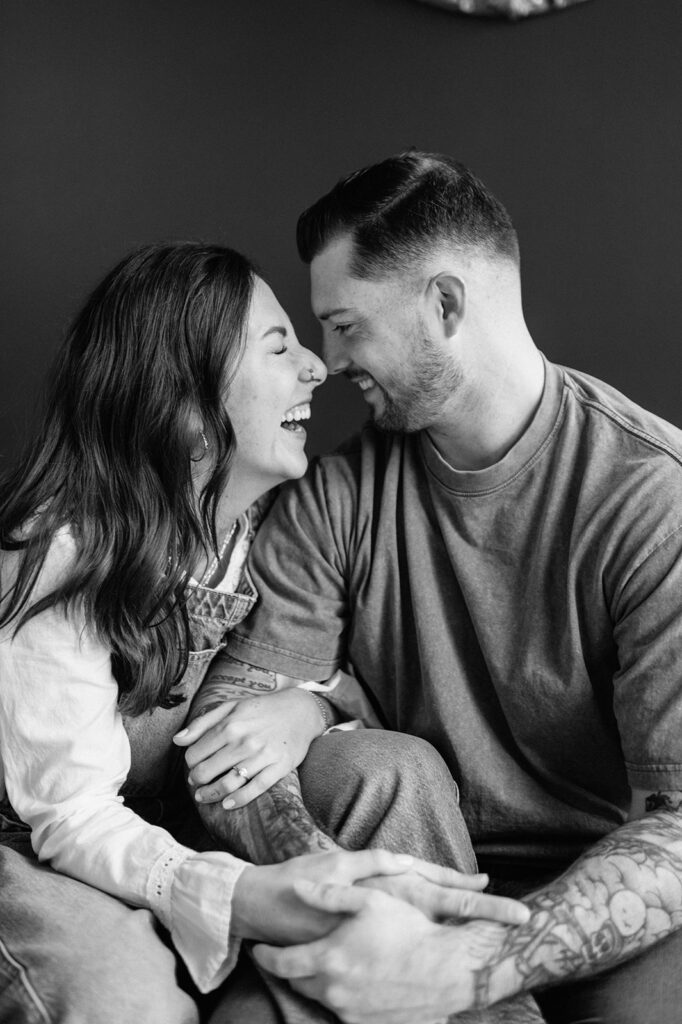 Black and white candid of couple laughing together during antique shop engagement photos.