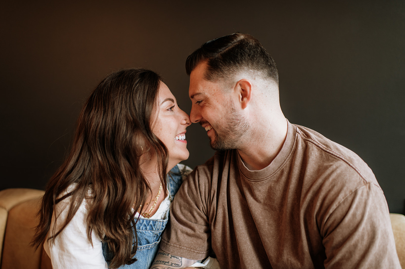 Couple laughing together on couch in antique shop engagement session.