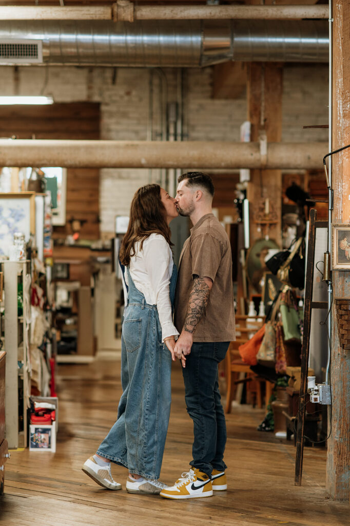 Couple kissing in antique store aisle during South Bend engagement photos.