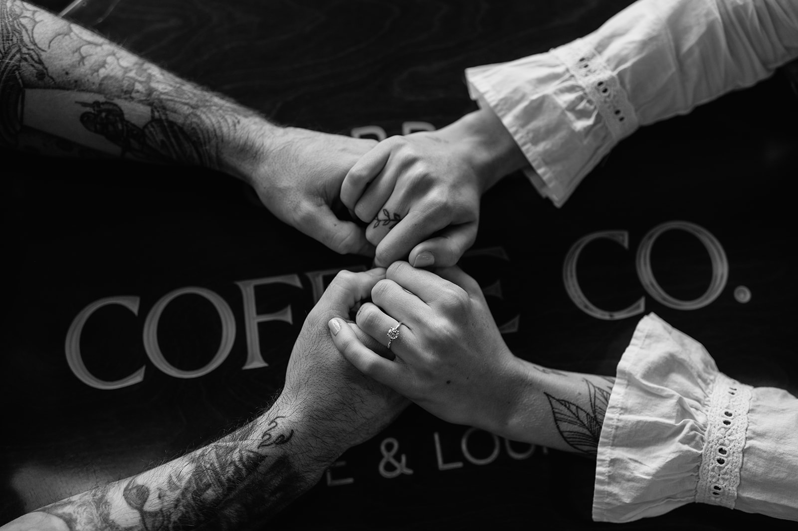 Close-up of couple holding hands with engagement ring.