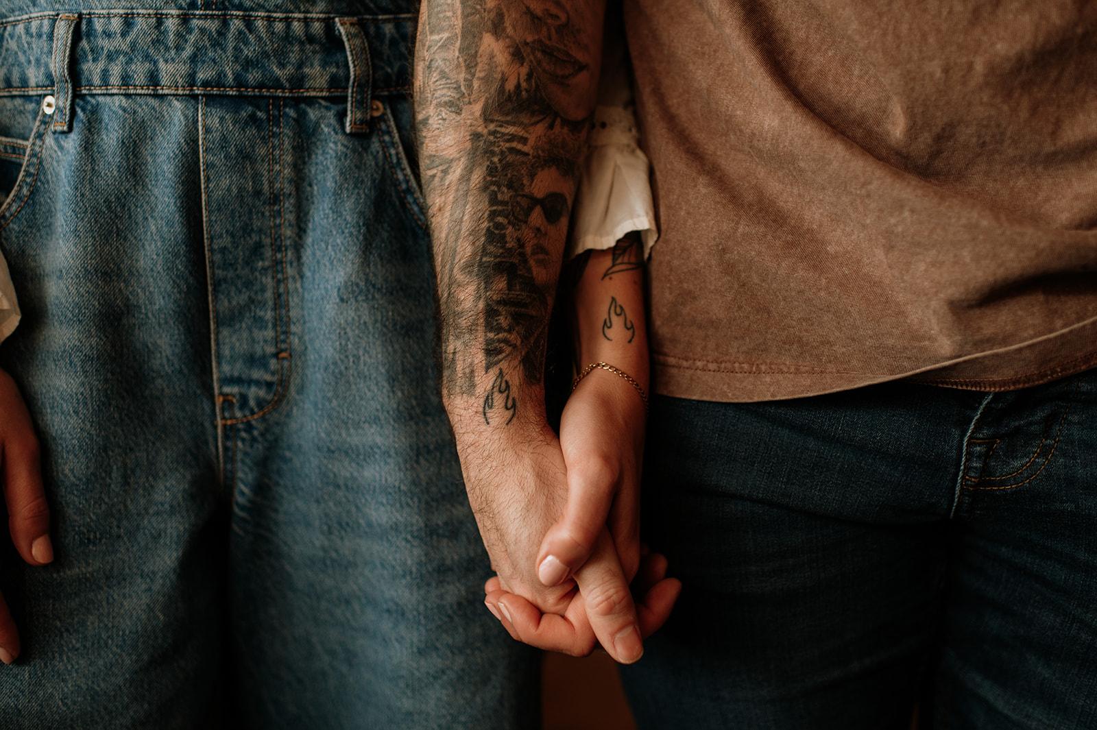 Close up photo of a couple with matching twin flame tattoos holding hands during their South Bend engagement session. 
