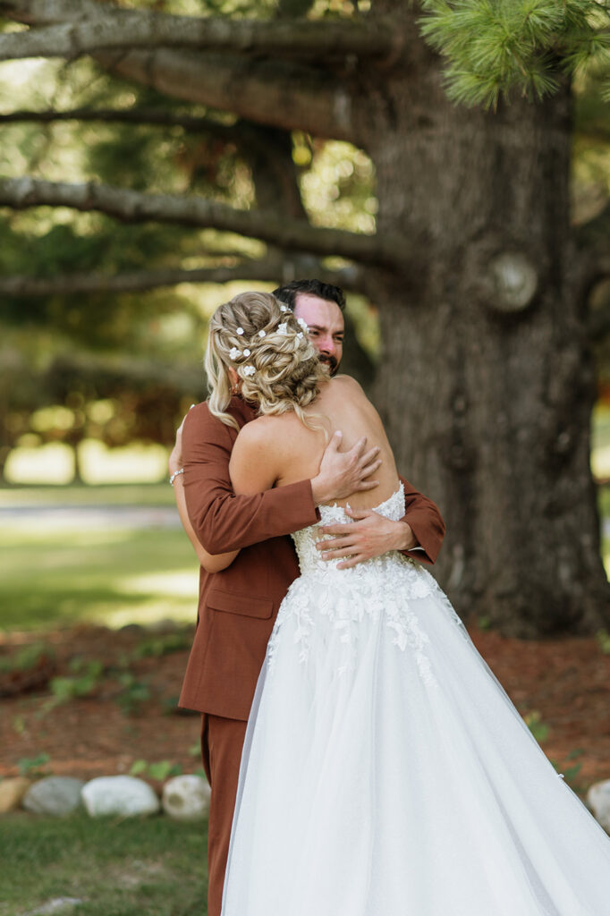 Bride and groom hugging during their emotional first look outdoors at The Lodge at Rush Lakes wedding venue.