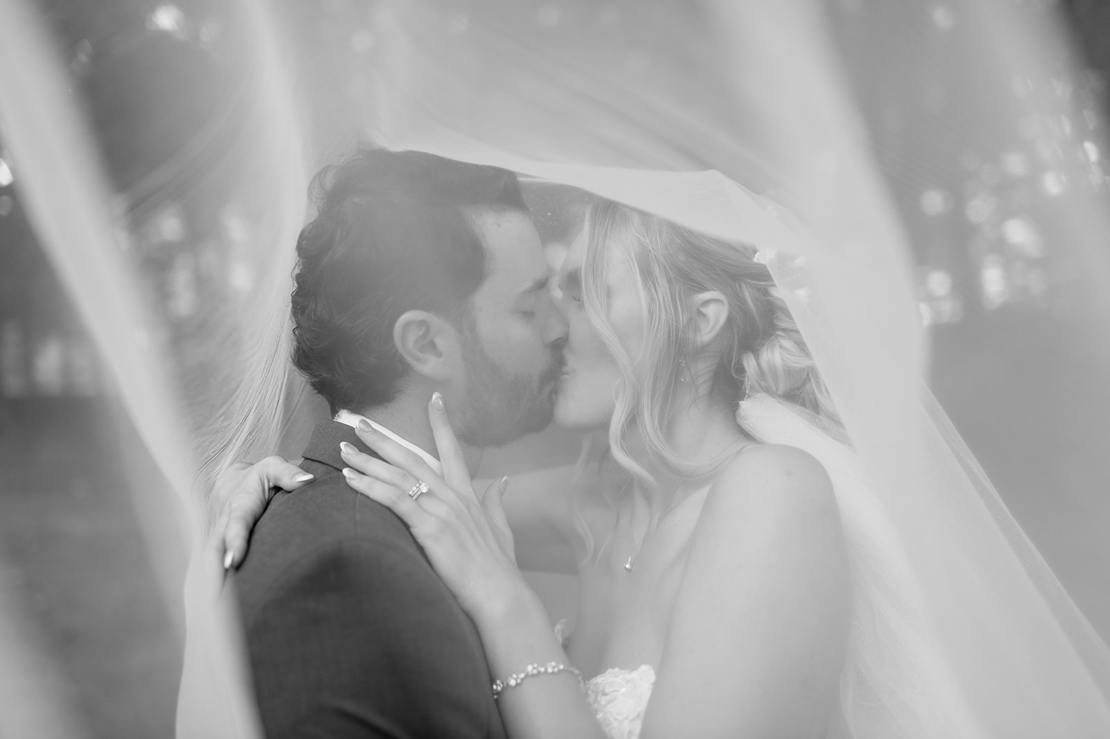 Bride and groom kissing under the veil during intimate wedding portrait.