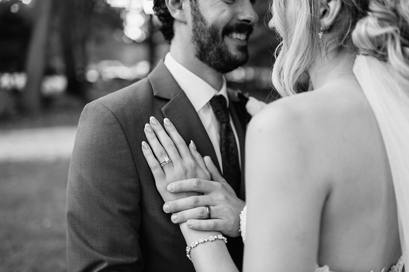 Bride resting her hand with engagement ring on groom’s chest during romantic portrait.