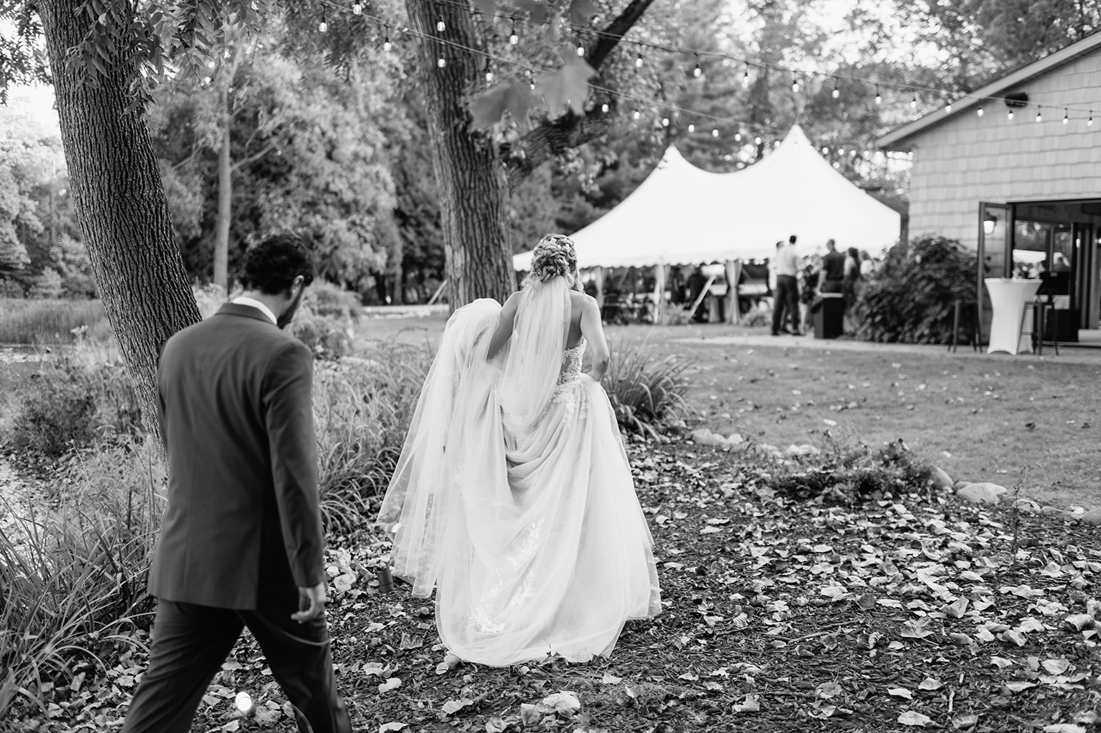 Black and white photo of a bride and groom walking back to The Lodge at Rush Lakes.