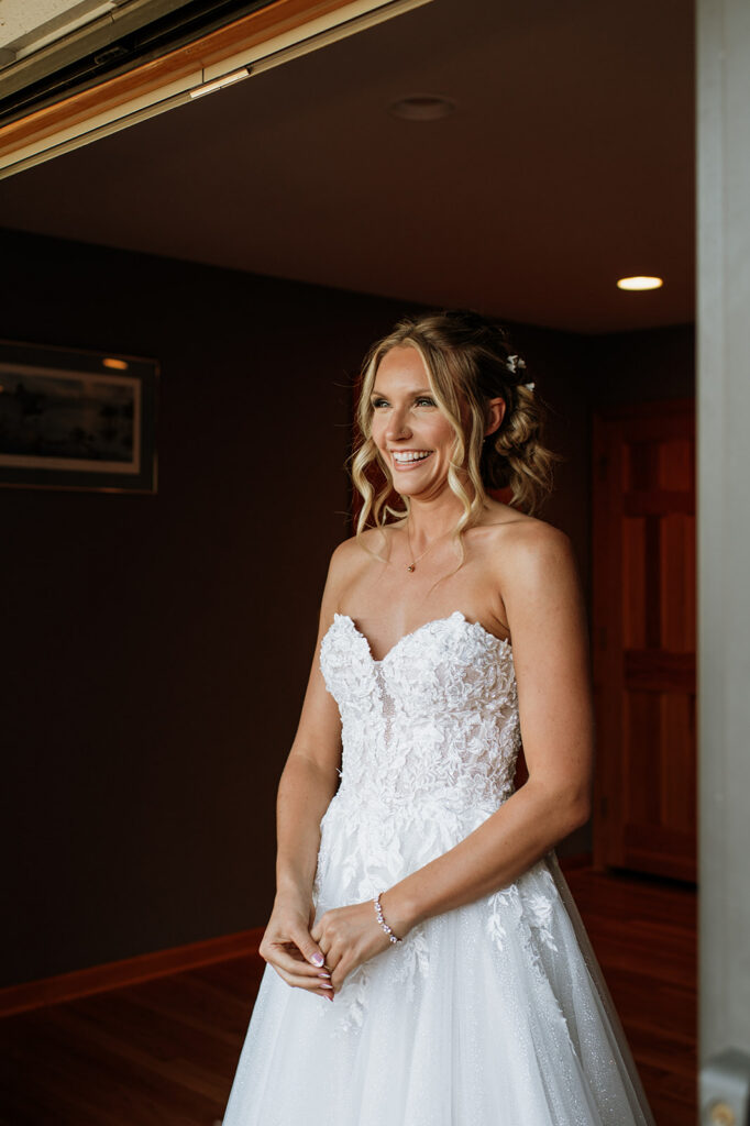 Bride smiling as she shares a first look with her bridesmaids. 
