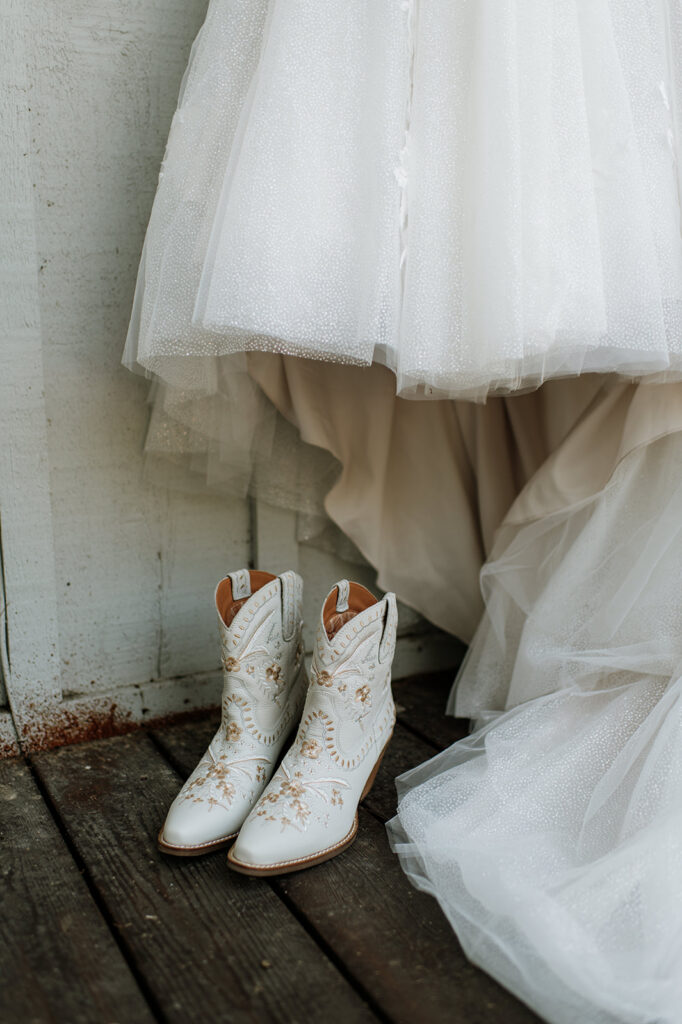 Close up shot of the brides white boots sitting next to her dress.