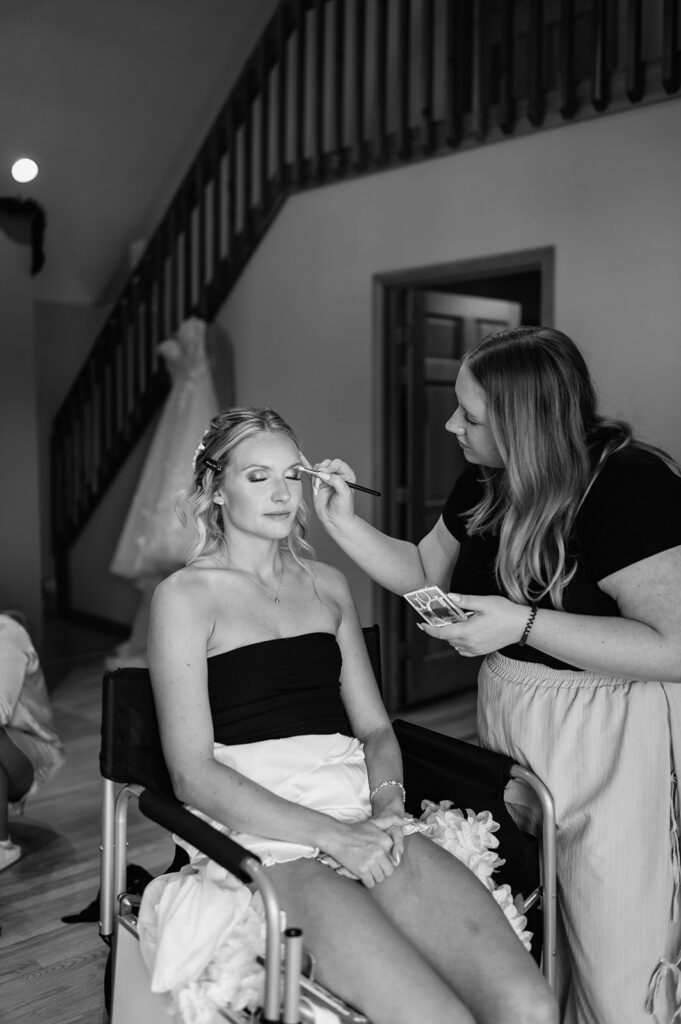 Black and white photo of a bride getting her makeup done.