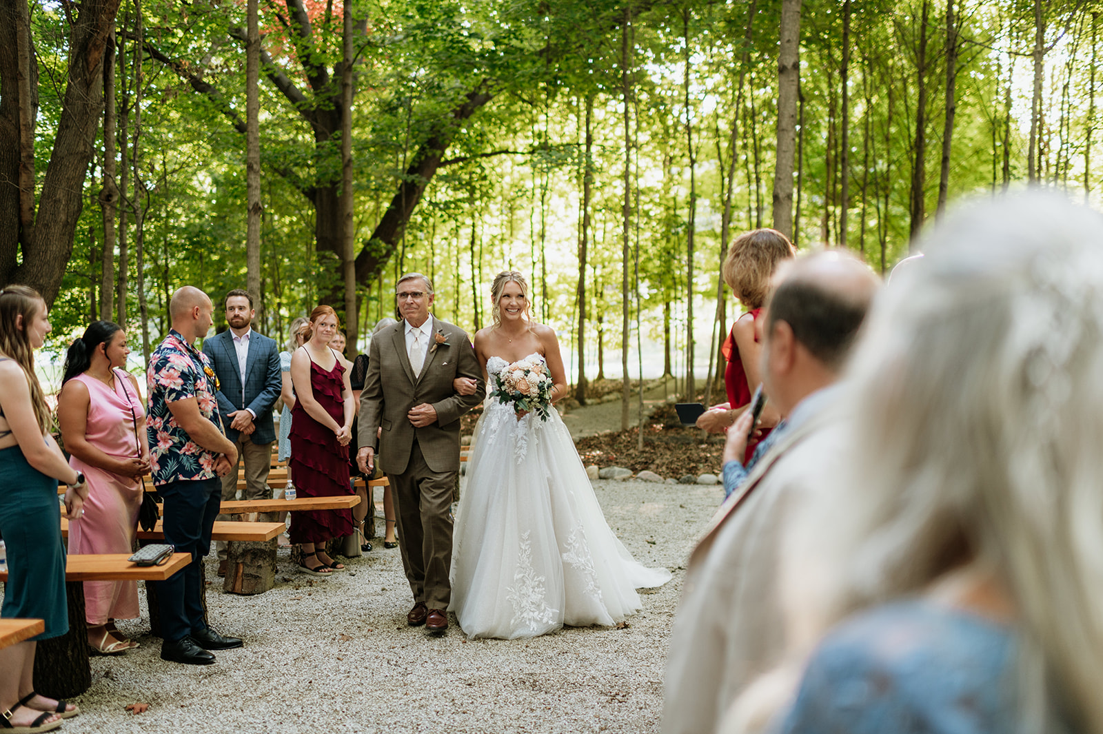 Bride walking down the aisle with her father during woodland ceremony at The Lodge at Rush Lakes.