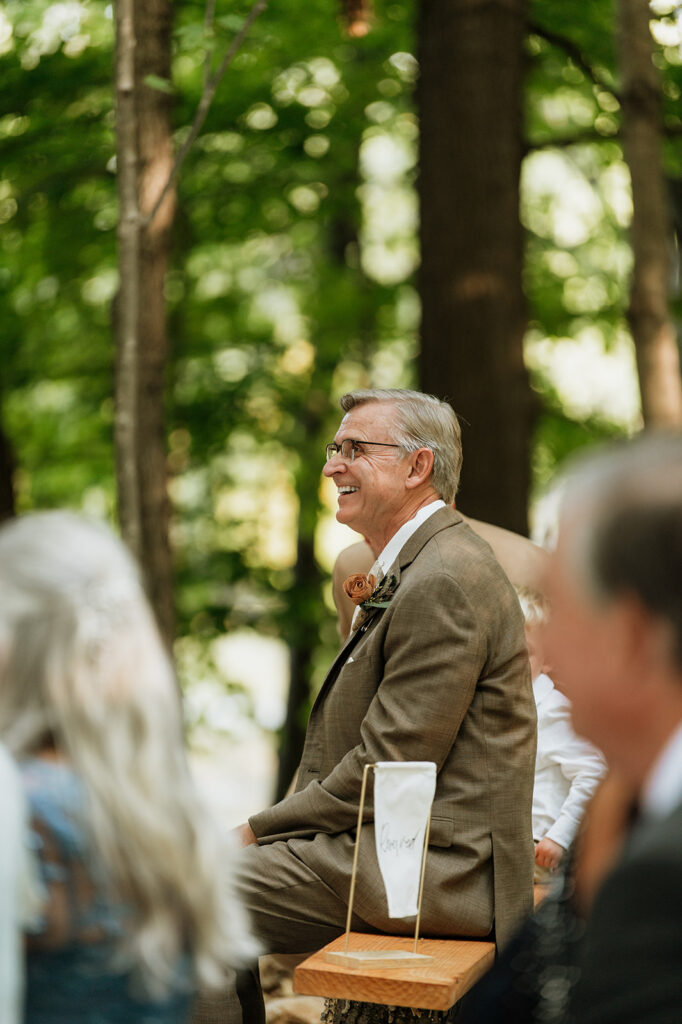 Father of the bride smiling during the ceremony.