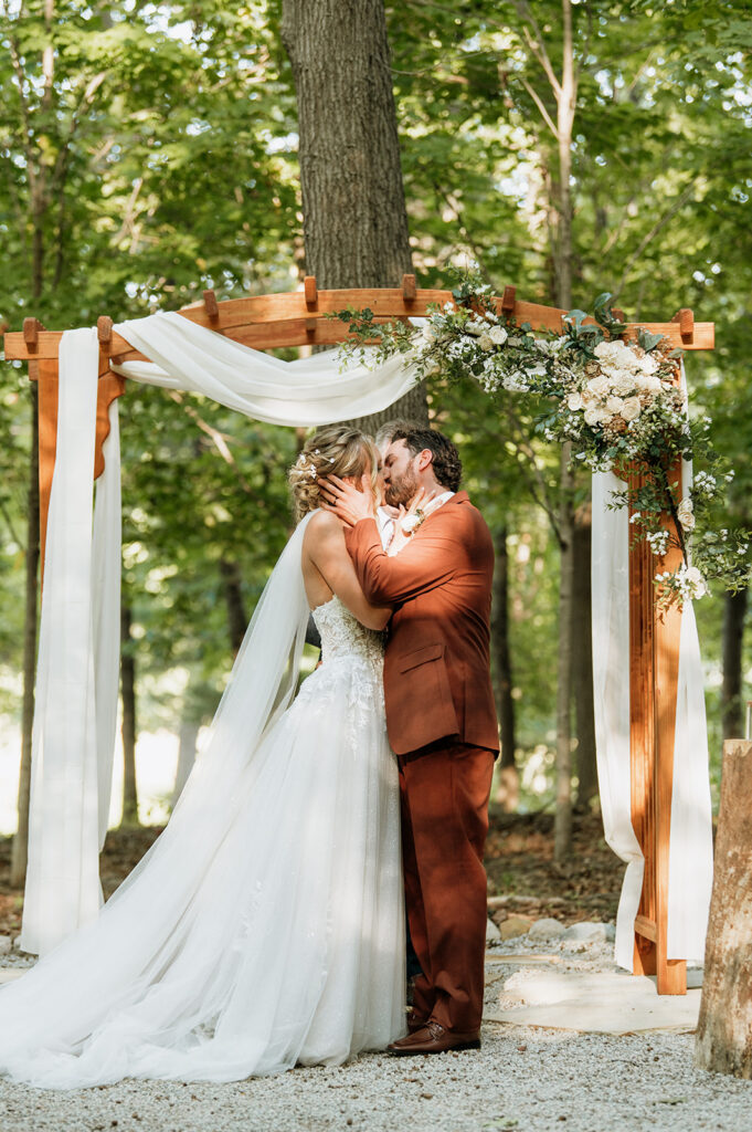 Bride and groom sharing their first kiss at the ceremony at The Lodge at Rush Lakes wedding.