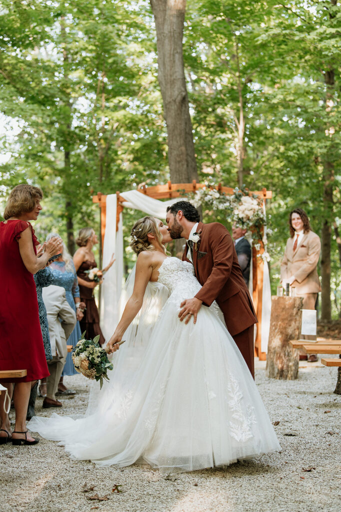 Bride and groom sharing an end of aisle dip kiss.