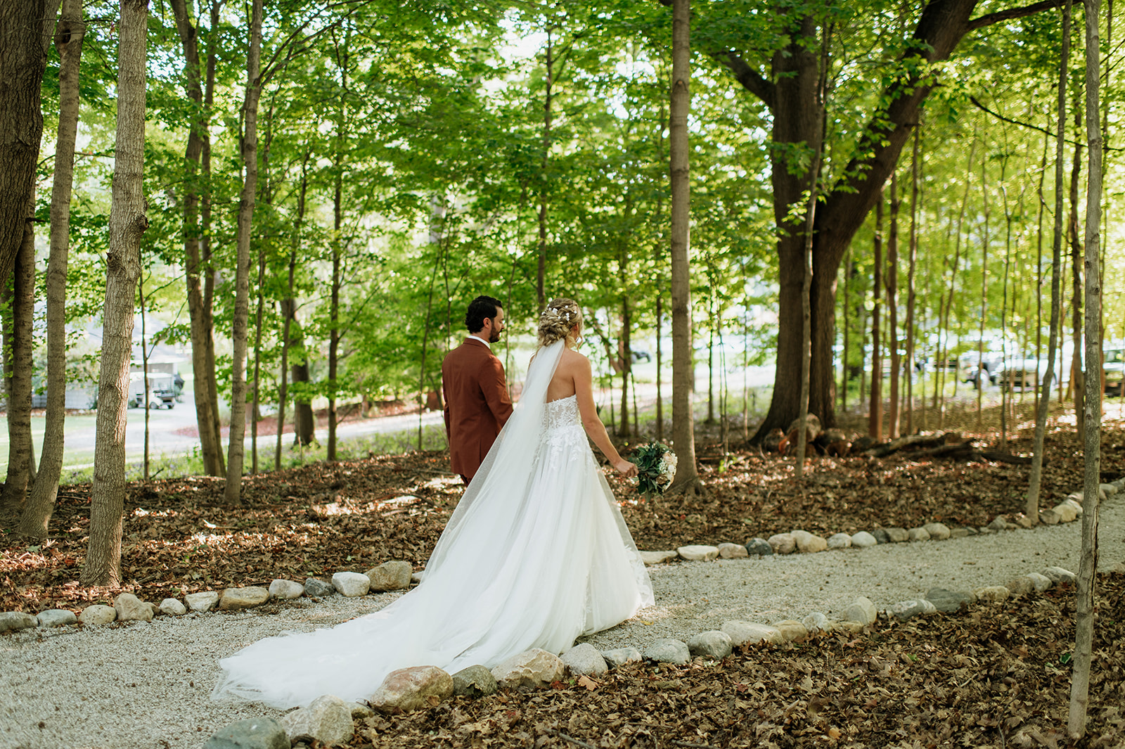Bride and groom walking through wooded path after their ceremony at The Lodge at Rush Lakes wedding venue.