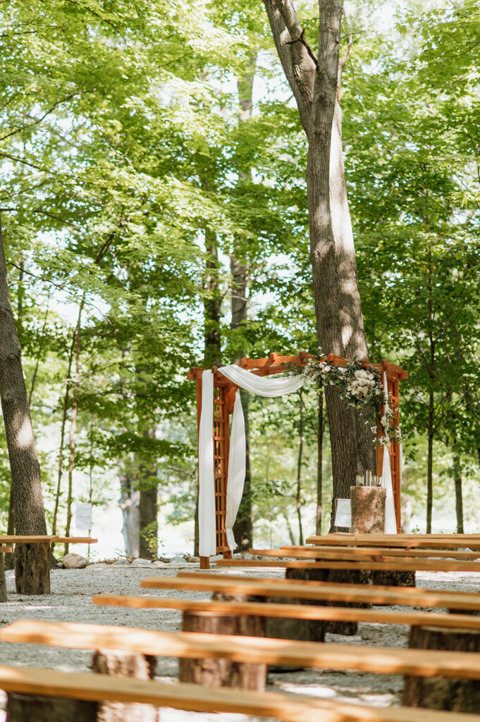 Outdoor wedding ceremony arbor surrounded by trees at The Lodge at Rush Lakes wedding venue.