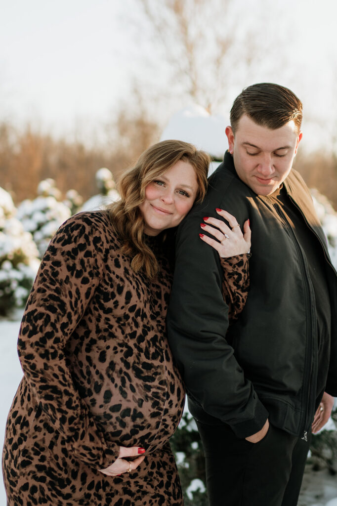 Expectant couple standing together at sunset during outdoor winter maternity photos in Northern Indiana.