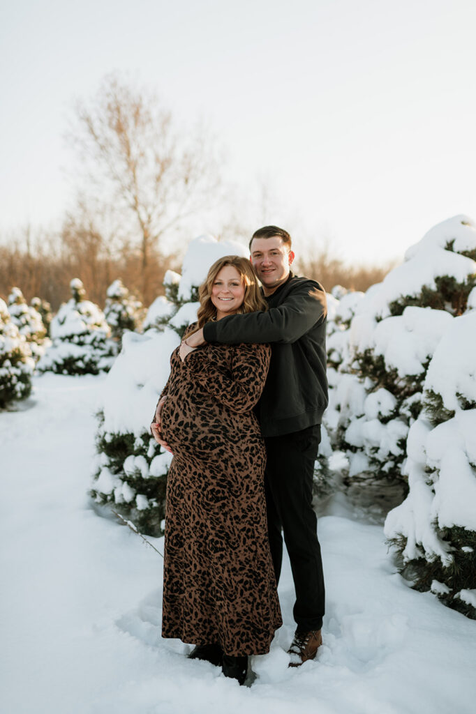 Expectant couple standing together at sunset during outdoor winter maternity photos in Northern Indiana.
