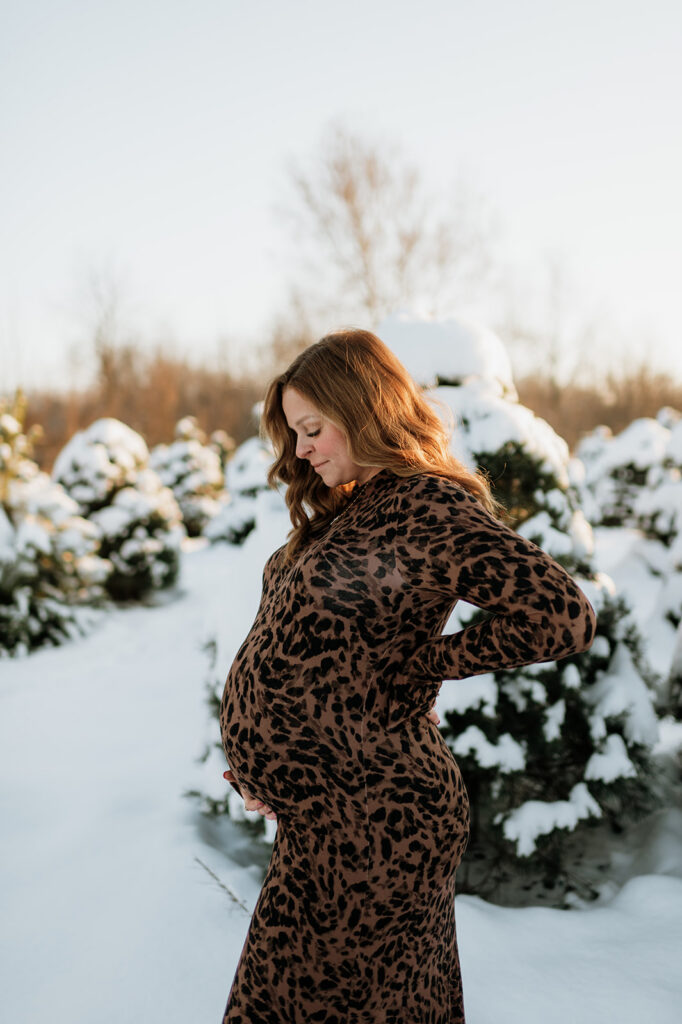 Outdoor winter maternity photo of a pregnant woman holding her belly at Flickinger Farms.