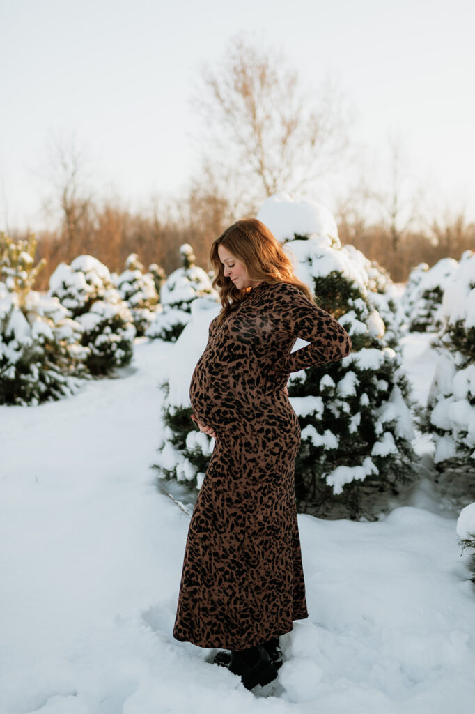 Outdoor winter maternity photo of a pregnant woman holding her belly at Flickinger Farms.