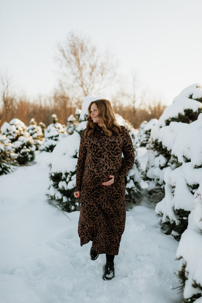 Outdoor winter maternity photo of a pregnant woman holding her belly at Flickinger Farms.