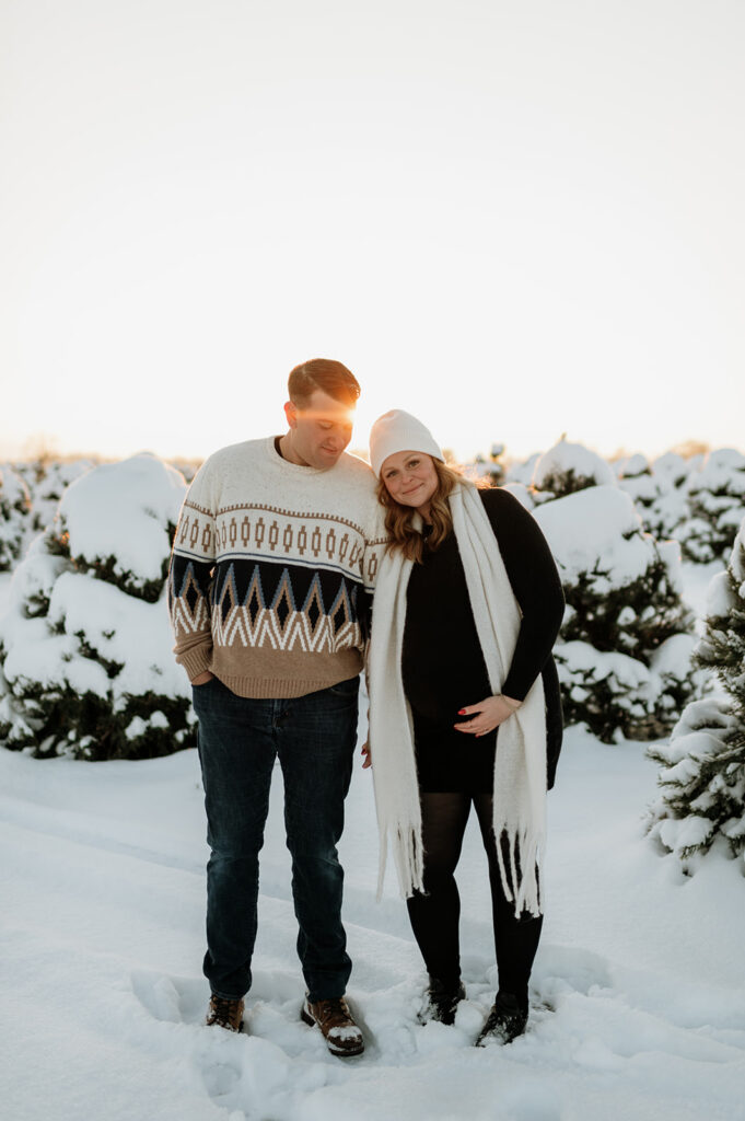 Couple standing together in a snowy evergreen tree farm in Northern Indiana.