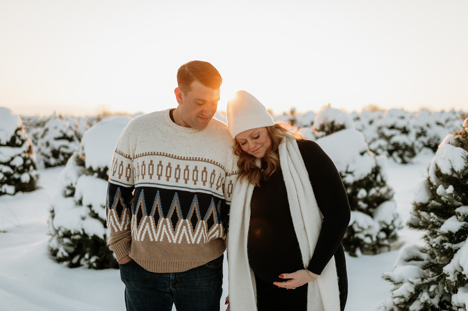 Couple posing during golden hour at a tree farm in Northern Indiana for their outdoor winter maternity photos.