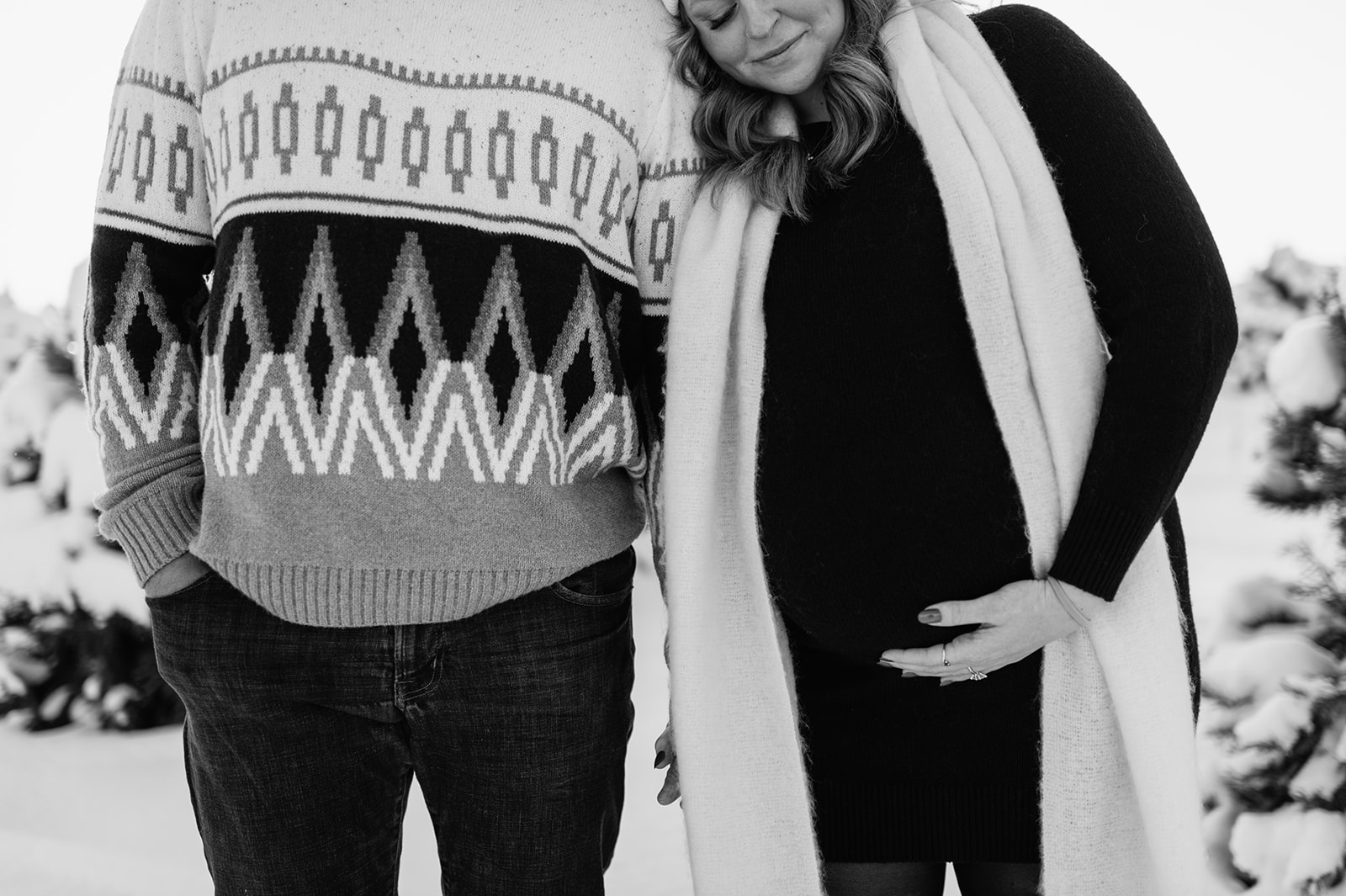Black and white photo of couple holding baby bump at a tree farm in Northern Indiana.