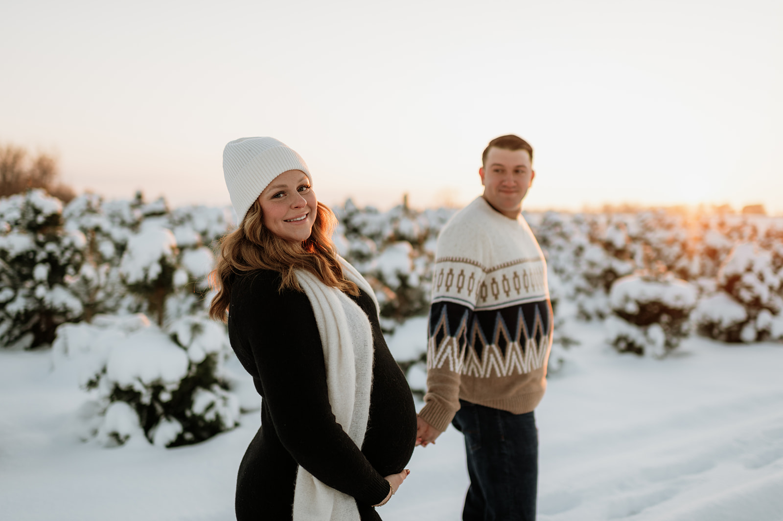 Pregnant woman smiling during sunset outdoor winter maternity photos at Flickinger Farms tree farm.