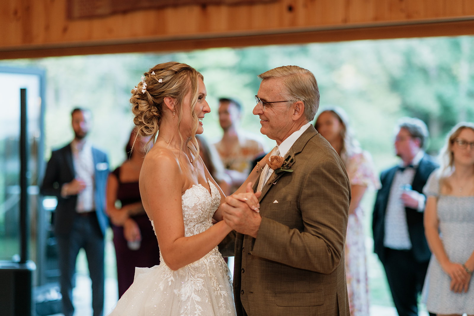 Bride sharing an emotional father-daughter dance during the reception while guests watch.