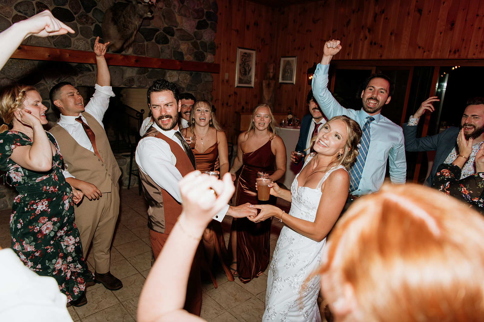 Bride and groom dancing with guests during a lively wedding dance floor celebration.