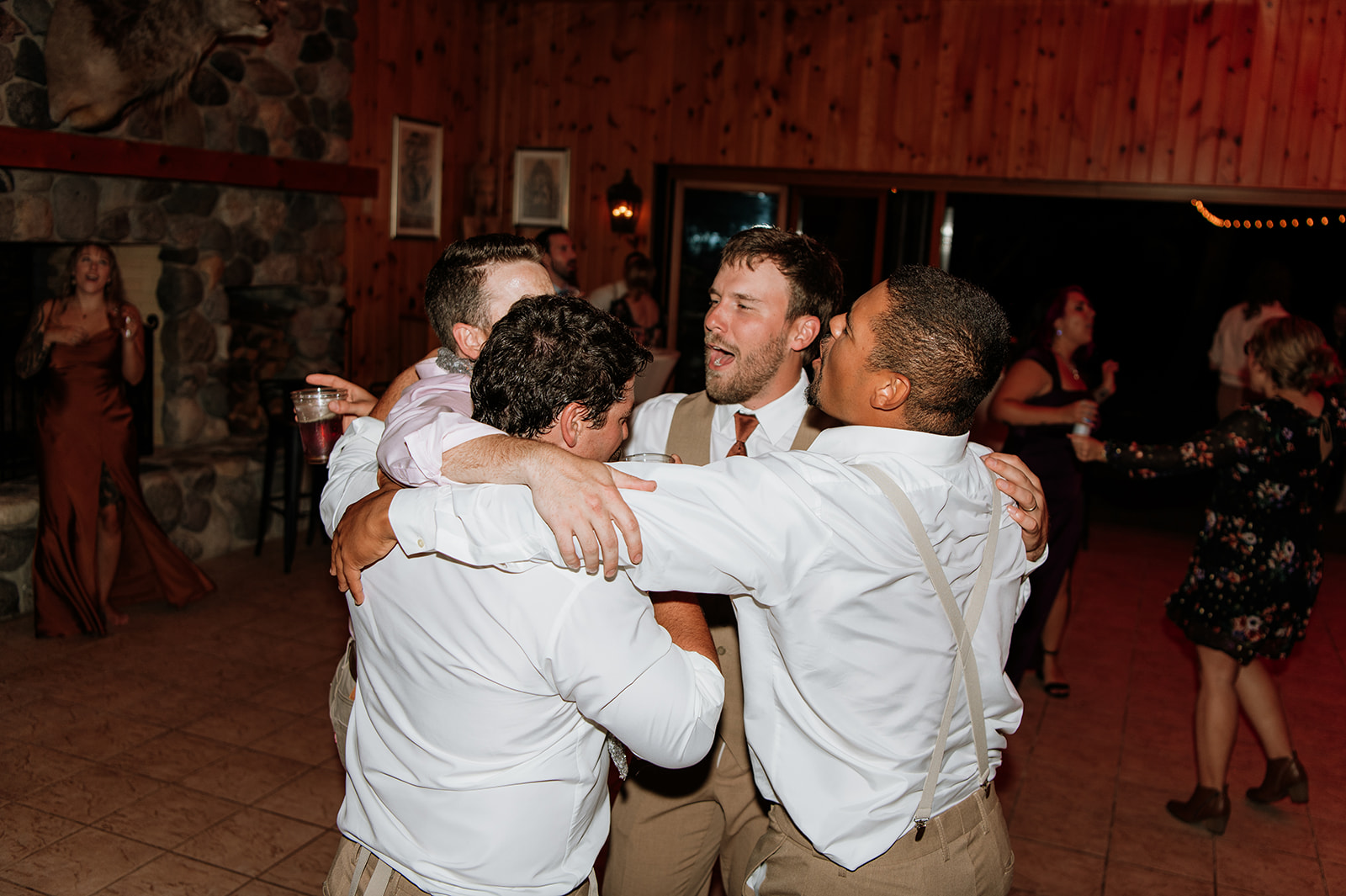 Groomsmen hugging and dancing together during a reception at The Lodge at Rush Lakes.