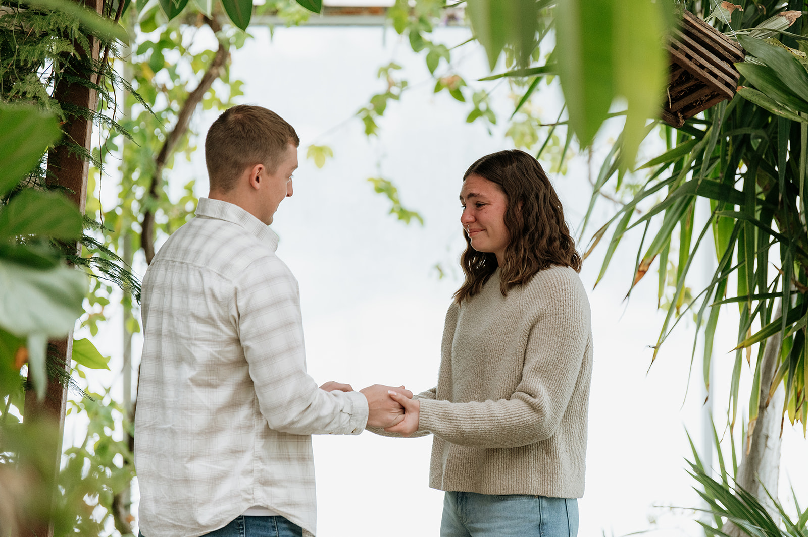 Emotional moment during a South Bend Indiana surprise proposal inside Potawatomi Conservatories surrounded by plants.