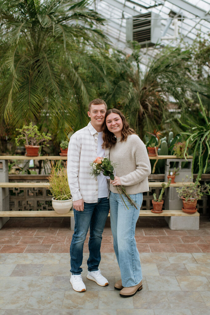 Couple smiling after their South Bend Indiana surprise proposal inside Potawatomi Conservatories greenhouse.