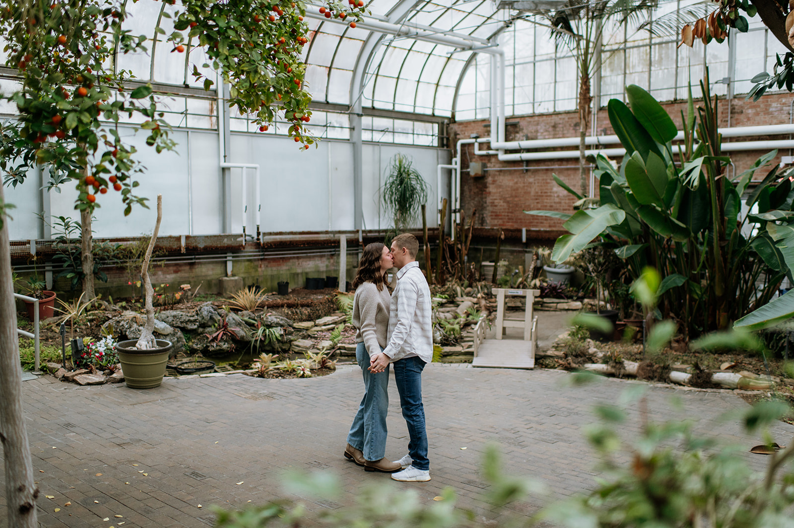 Wide shot of a couple kissing at Potawatomi Conservatories.