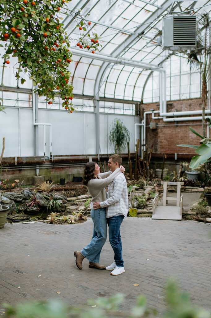Couple hugging during their indoor proposal at Potawatomi Conservatories.
