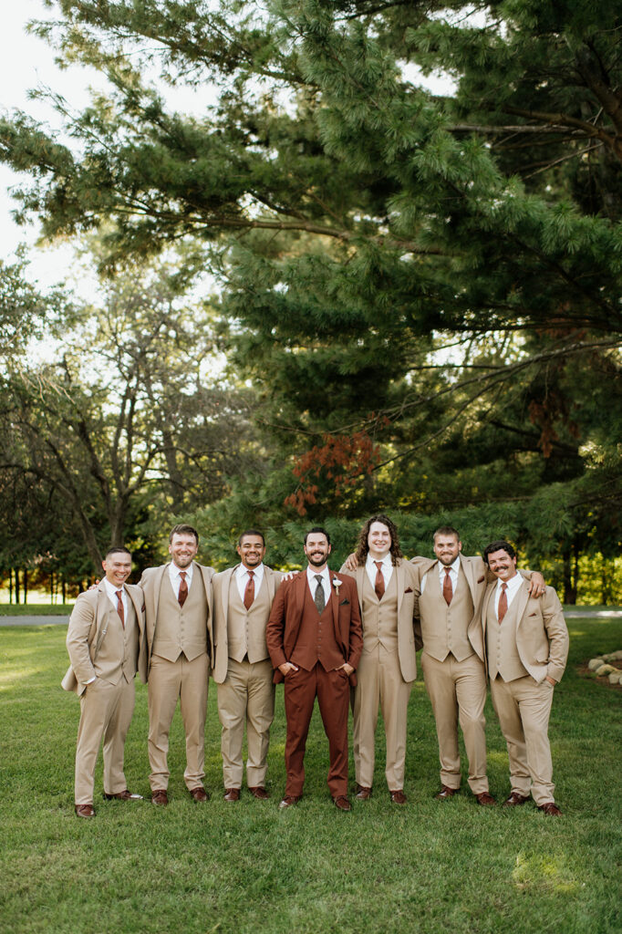 Groom with groomsmen wearing tan suits during wedding party portraits at The Lodge at Rush Lakes.