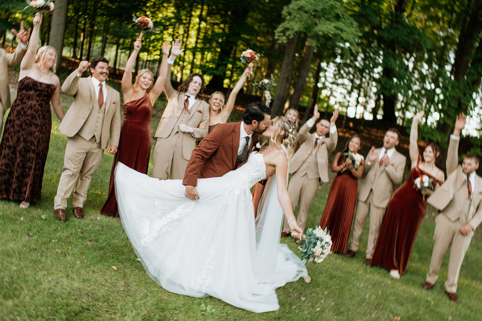 Bride and groom dip kiss while wedding party celebrates around them at The Lodge at Rush Lakes wedding venue.